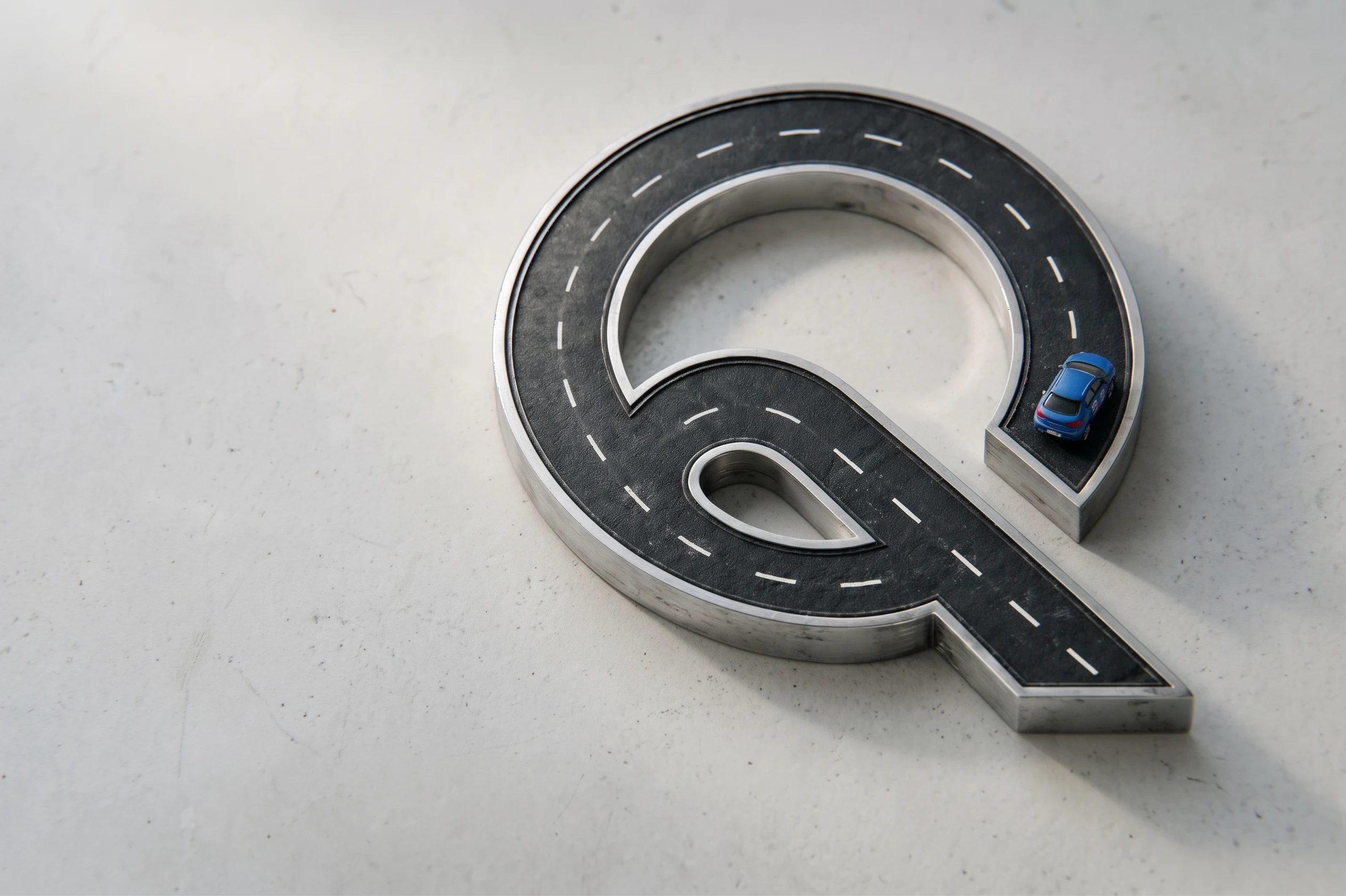 Eine Strasse in Form des Quick-Drive-Logos mit einem blauen Fahrschulauto